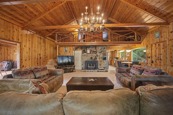 Gather around the stone fireplace in this stunning great room where rustic wood beams and a crystal chandelier create the perfect atmosphere for your mountain getaway.
