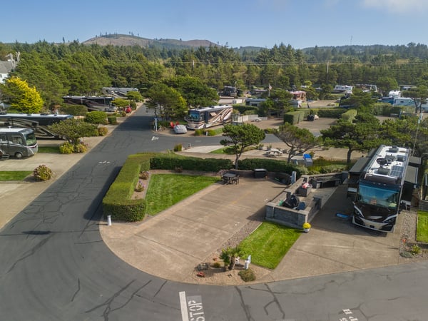 Aerial view of the RV park surrounded by lush greenery and distant hills, providing a peaceful arrival experience.