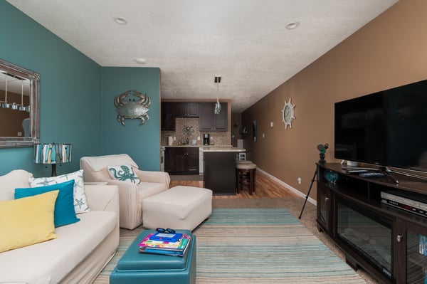 Relax in your coastal-themed living space, where cozy seating meets a well-equipped kitchenette—perfect for unwinding after a day of adventure.