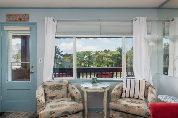 Your cozy sunroom retreat overlooks lush greenery—ideal for your morning coffee or quiet afternoon with a book, surrounded by coastal charm and comfort.