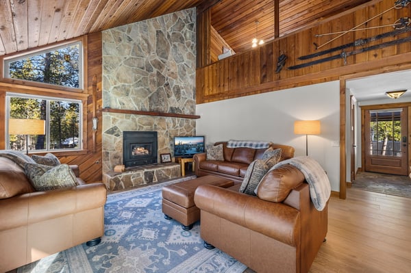 Cozy up by your stone fireplace in this warm living room with leather seating and rustic wood beams overhead.