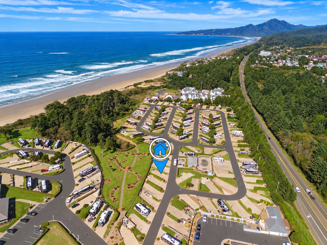 Aerial view of the property showcasing its prime beachfront location, surrounded by lush forests and offering direct access to the stunning sandy shore and ocean beyond.