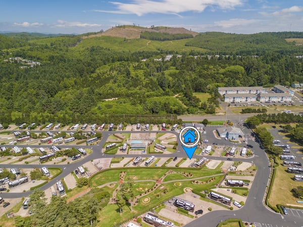 Aerial view of a vacation rental community nestled among lush forests and rolling hills, with scenic mountain terrain defining the natural landscape.