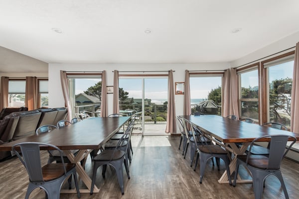 Gather around spacious dining tables with stunning coastal views framing every meal. Natural light fills the room as gentle breezes drift through open glass doors, creating a perfect setting for memorable moments.
