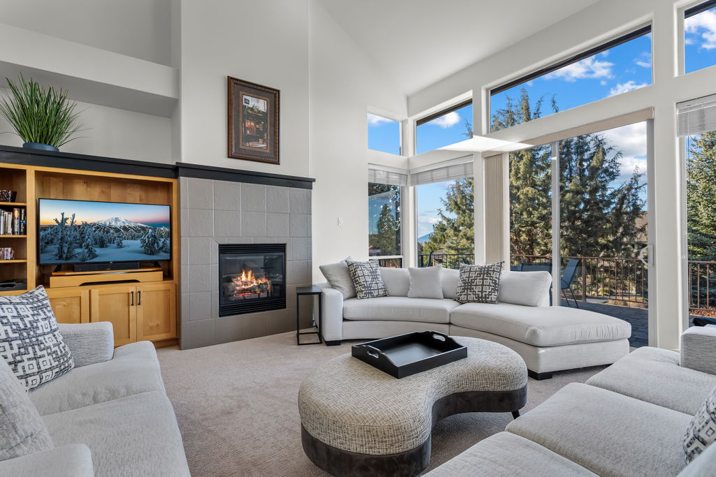 Unwind in your spacious living room where plush seating surrounds a cozy fireplace, while floor-to-ceiling windows frame stunning mountain views.