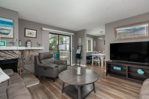 Unwind in your bright, welcoming living room with coastal-inspired touches, comfy seating, and a cozy fireplace—perfect for relaxing after a day exploring the area.