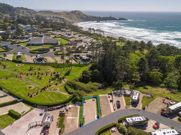 Aerial view showcasing a coastal property set against sweeping ocean vistas, verdant hills, and sandy beaches. The surrounding neighborhood features well-maintained grounds and proximity to natural landmarks.