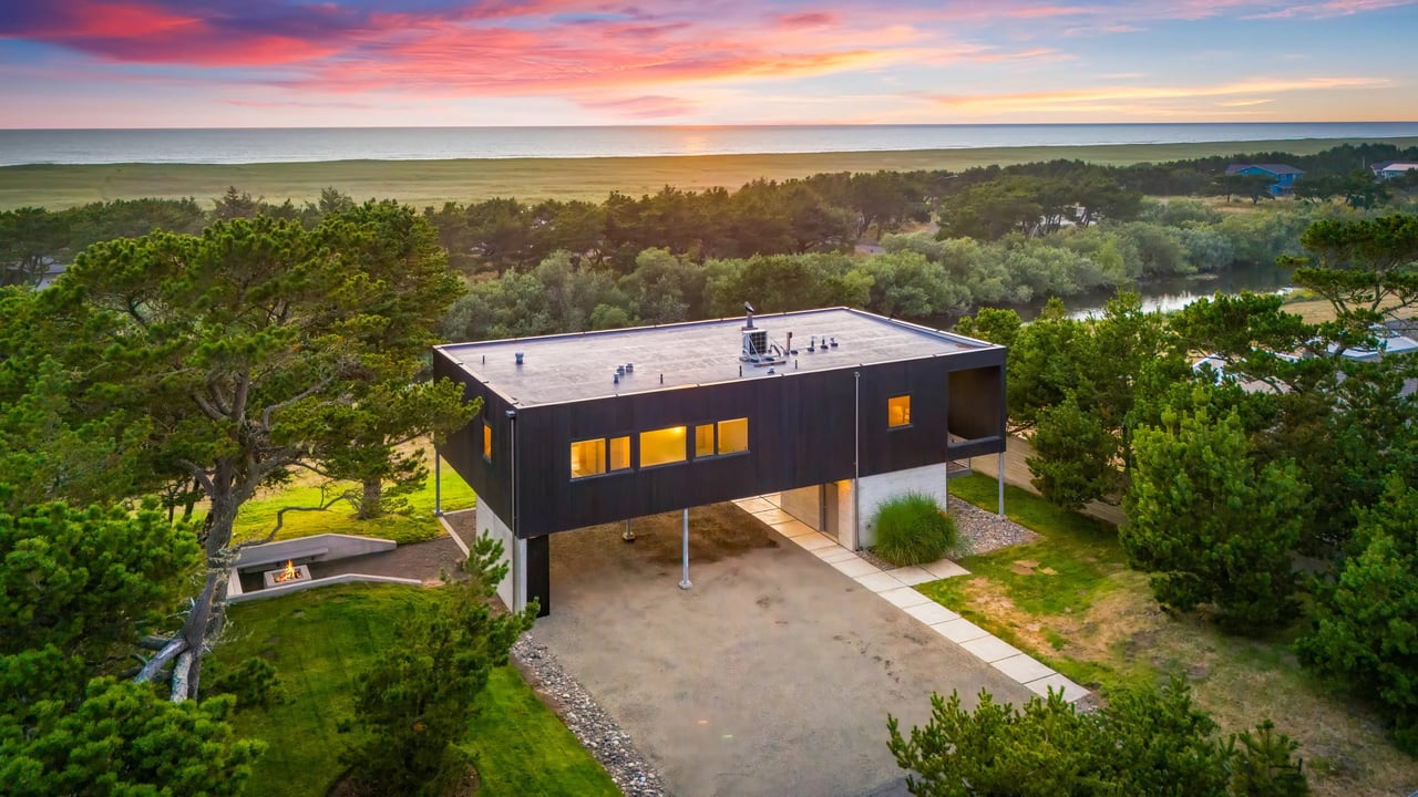 Modern architectural design meets coastal tranquility. This striking property features dramatic sunsets over the sea and expansive natural surroundings with mature trees and water views.
