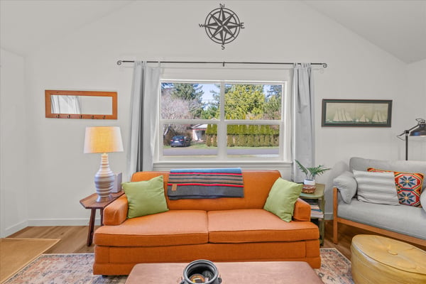 Relax in your bright living room with vibrant orange sofa and cozy reading nook by the window.