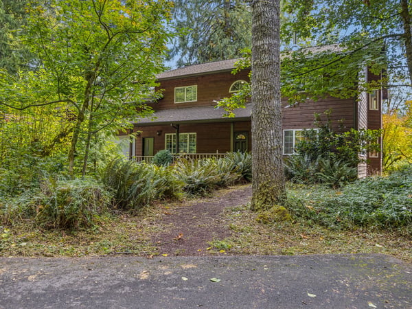 A charming wood cabin nestled among towering trees and lush greenery, offering a peaceful retreat surrounded by nature.