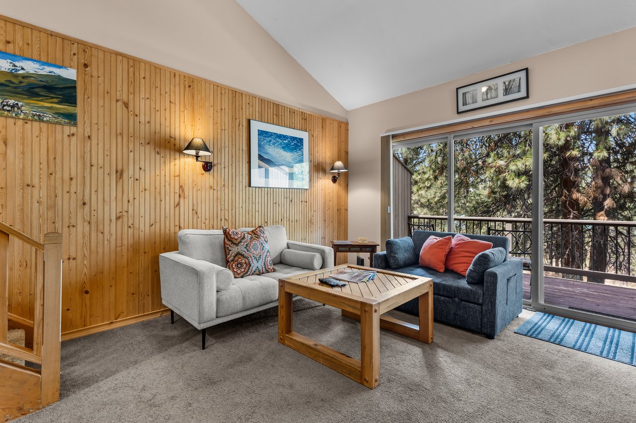Settle into your cozy living room with vaulted ceilings and warm wood accents, where soft seating and natural light invite you to relax after a day of adventure.
