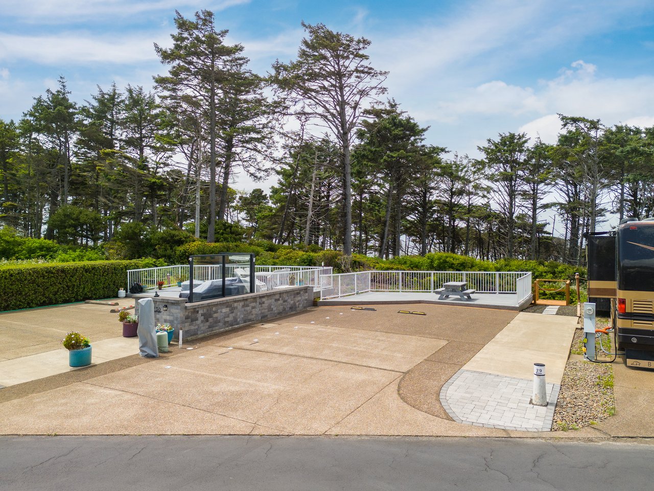 Spacious outdoor area featuring covered seating pavilions, green landscaping, and scenic tree-lined surroundings perfect for relaxation and gathering under the coastal sky.
