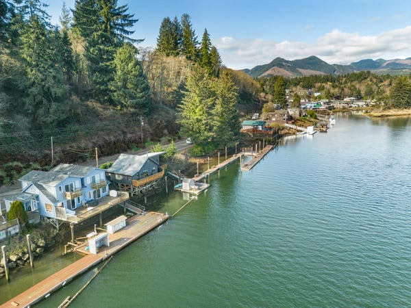 Scenic waterfront community nestled between forested hills and pristine lake waters with mountain backdrop.